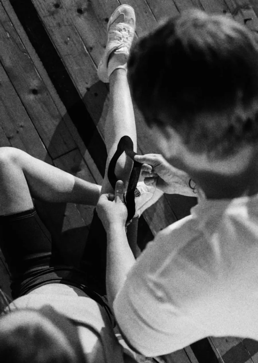 A man applying athletic tape to a man's leg